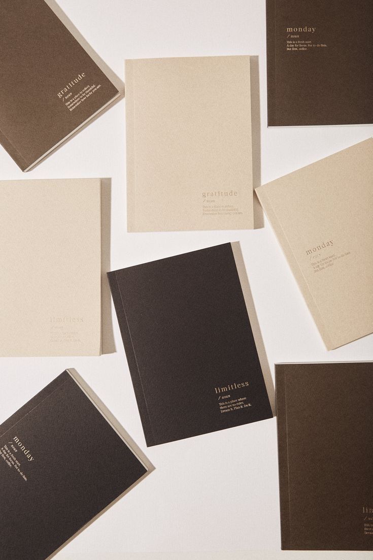 Cream and dark-brown minimalist notebooks scattered on a light surface